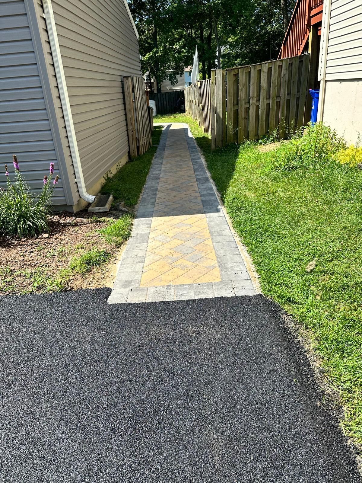 A sidewalk leading to a house next to a fence.