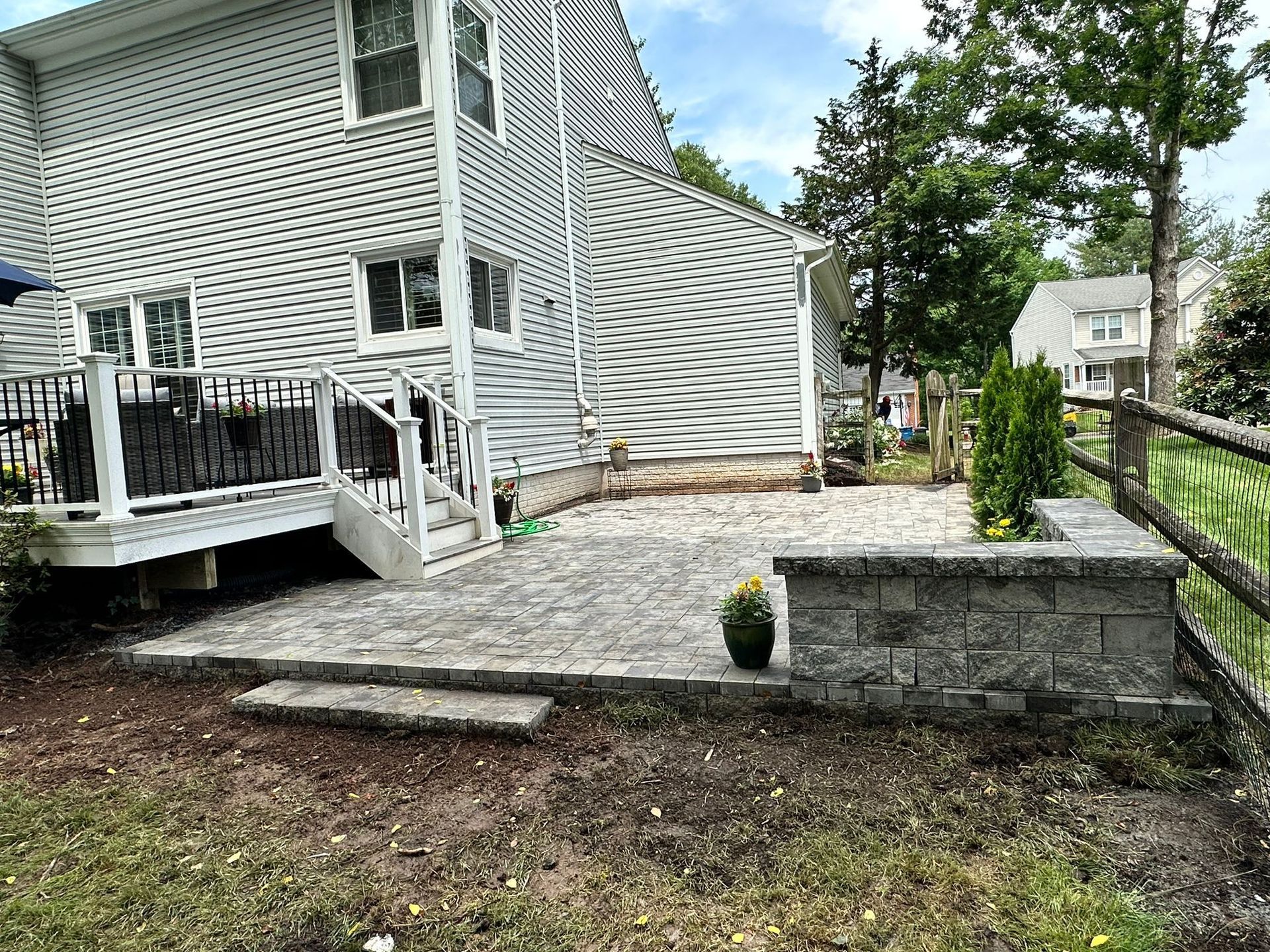 The backyard of a house with a patio and a wooden fence.