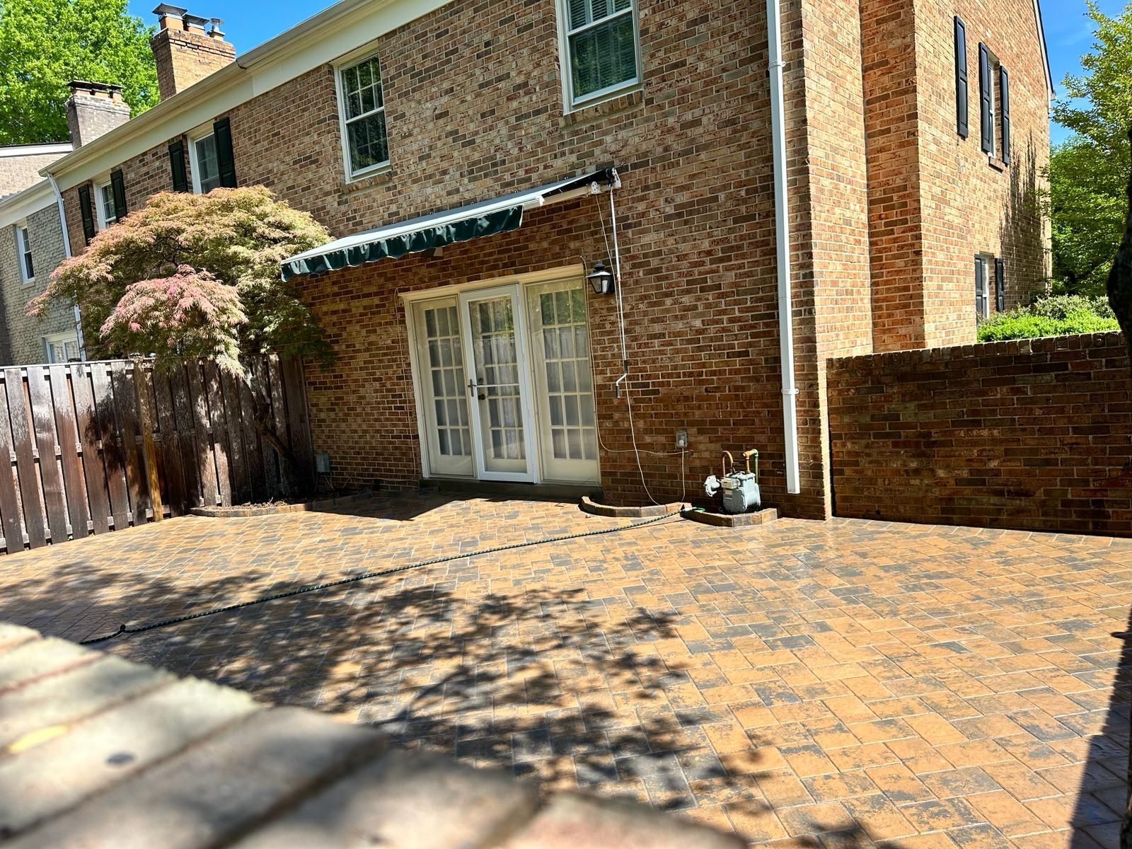A brick house with a patio and a wooden fence in front of it.