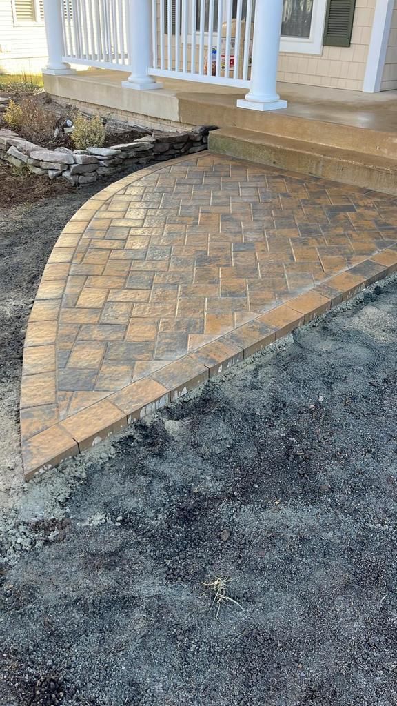 A brick walkway is being built in front of a house.
