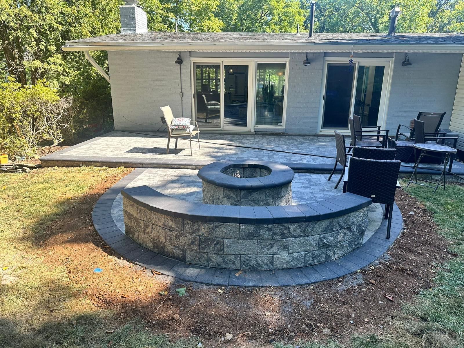 A fire pit is sitting in the middle of a patio in front of a house.