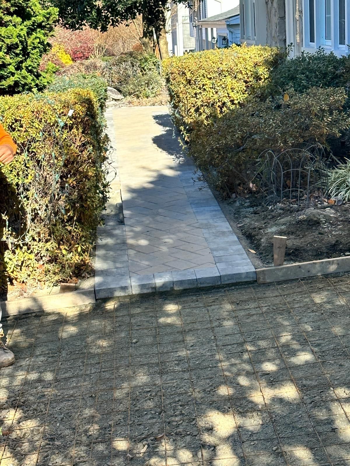 A person is walking down a sidewalk next to a house.