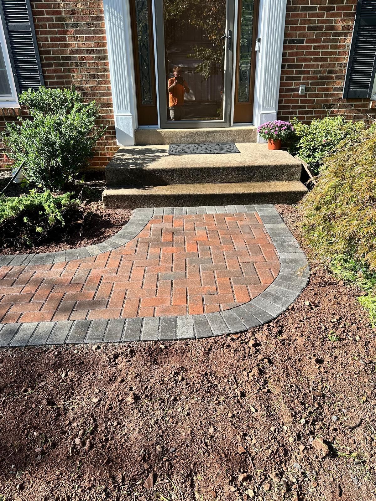 A brick walkway leading to the front door of a brick house.