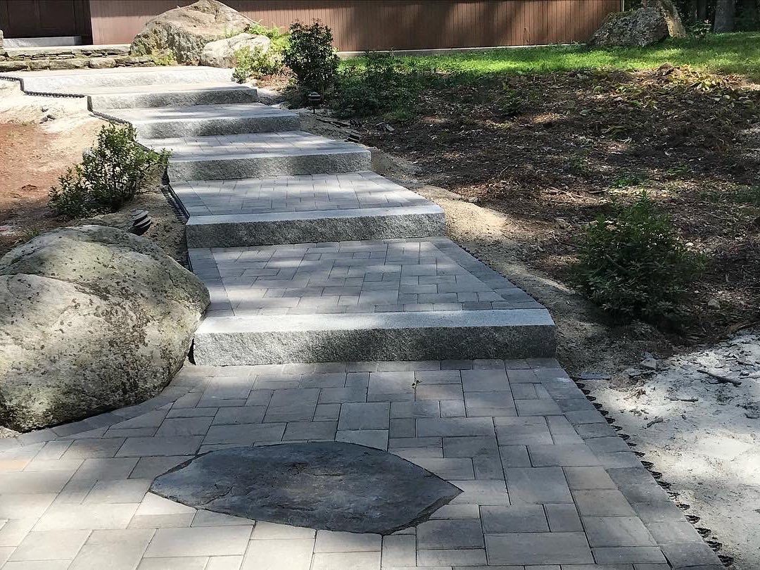 A brick walkway with stairs leading up to a house.