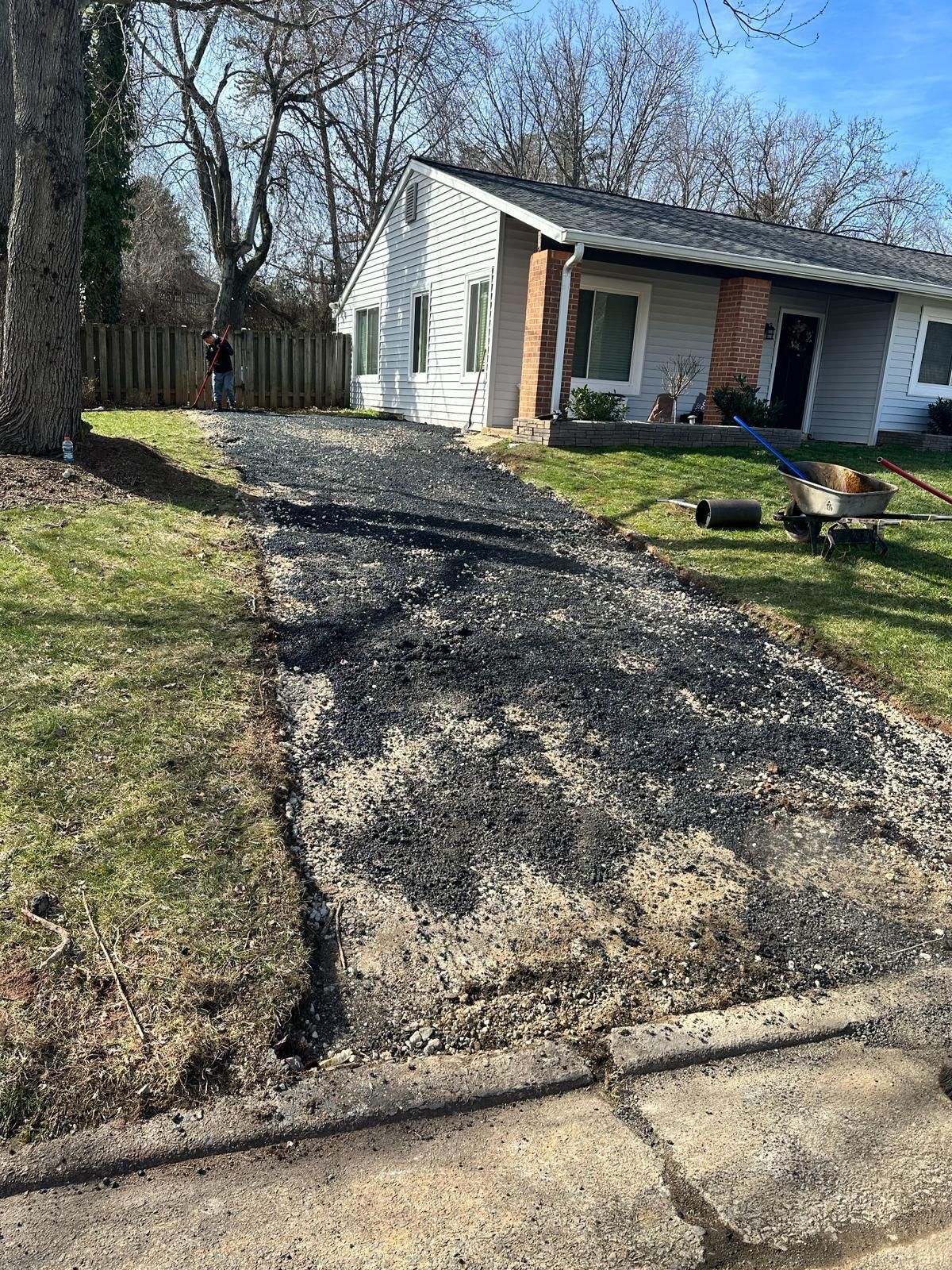 A white house with a black driveway in front of it.