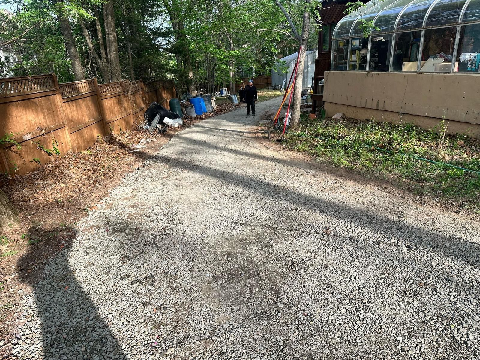 A gravel road with a greenhouse in the background.