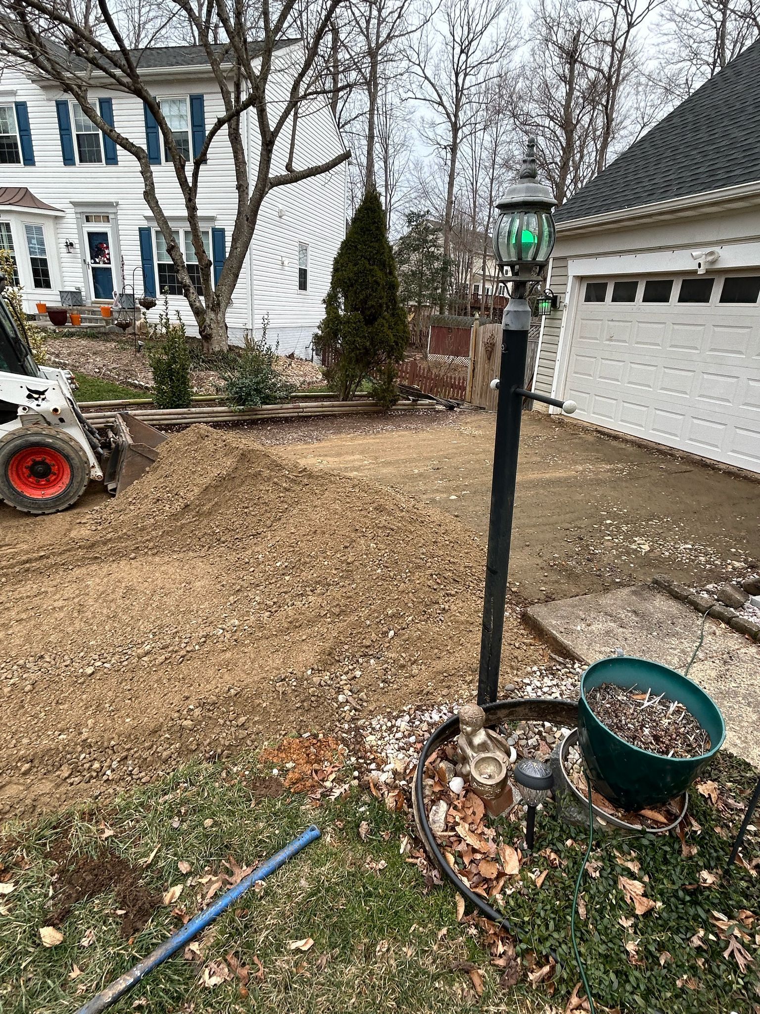 A bobcat is moving dirt in a yard in front of a house.
