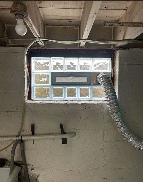 A window in a basement with a hose coming out of it.