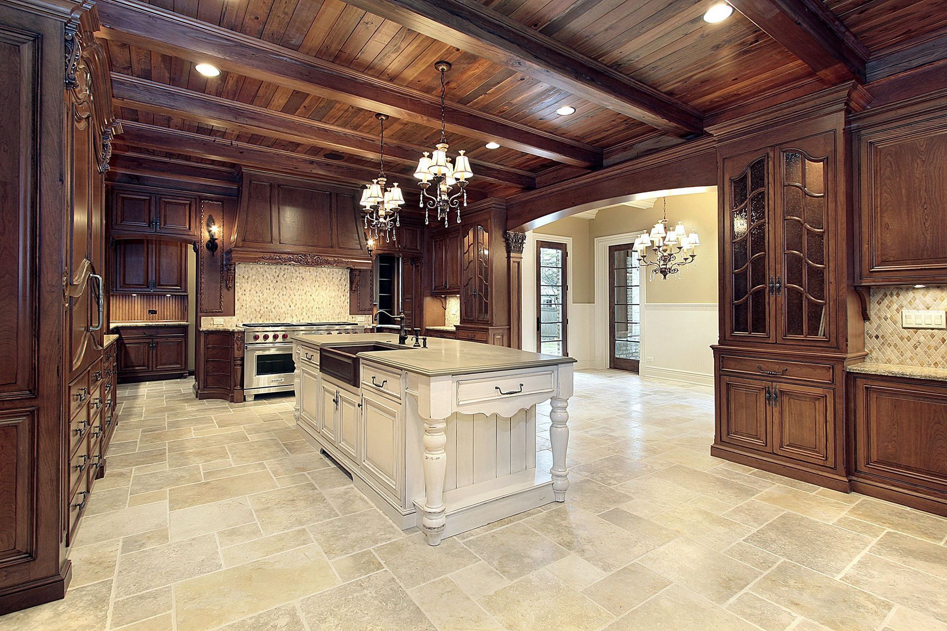 Luxury kitchen with dark wood cabinetry, marble island, and stone tile floor