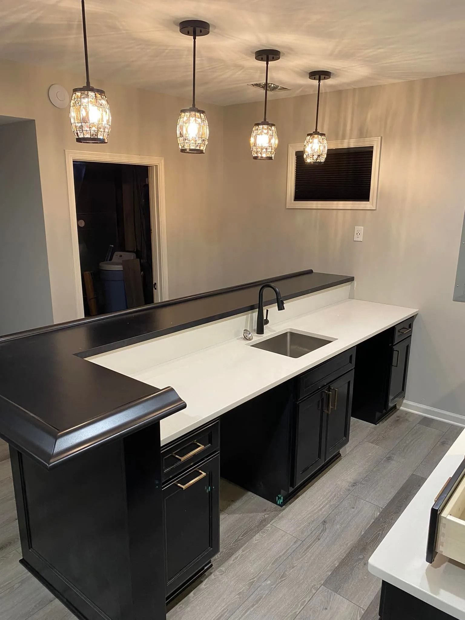 Modern kitchen island with black-and-white counters, pendant lights, and gray flooring