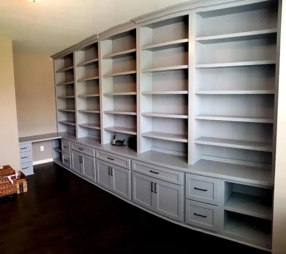 Built-in white bookshelves with cabinets in a bright empty room