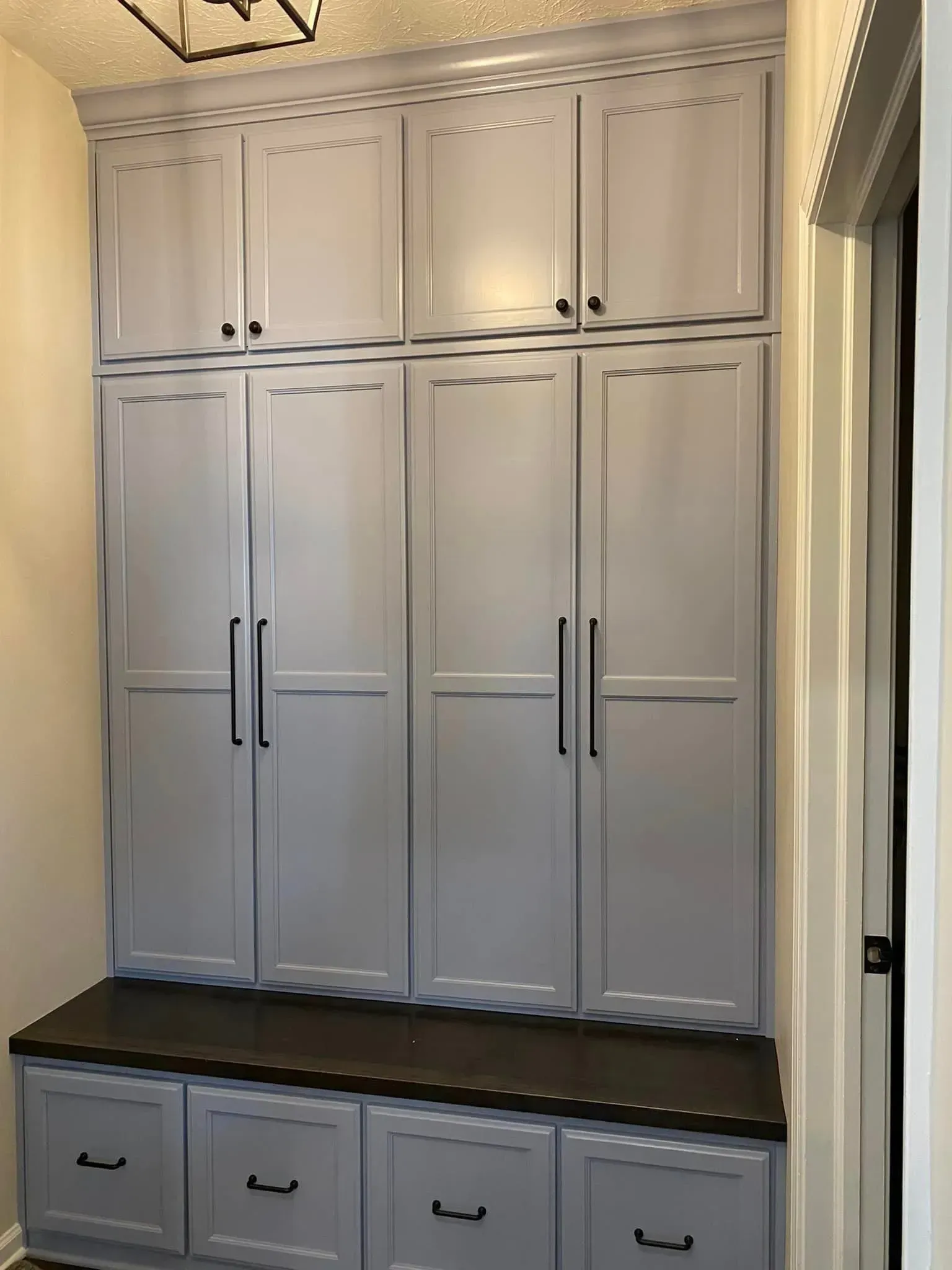 Built-in gray cabinet wall with storage drawers and dark countertop in a narrow hallway