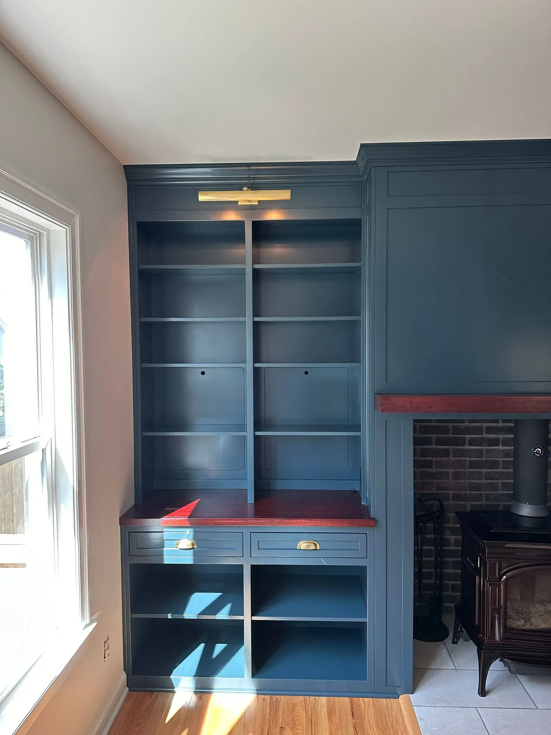 Built-in blue desk and shelves beside a fireplace in a sunlit room