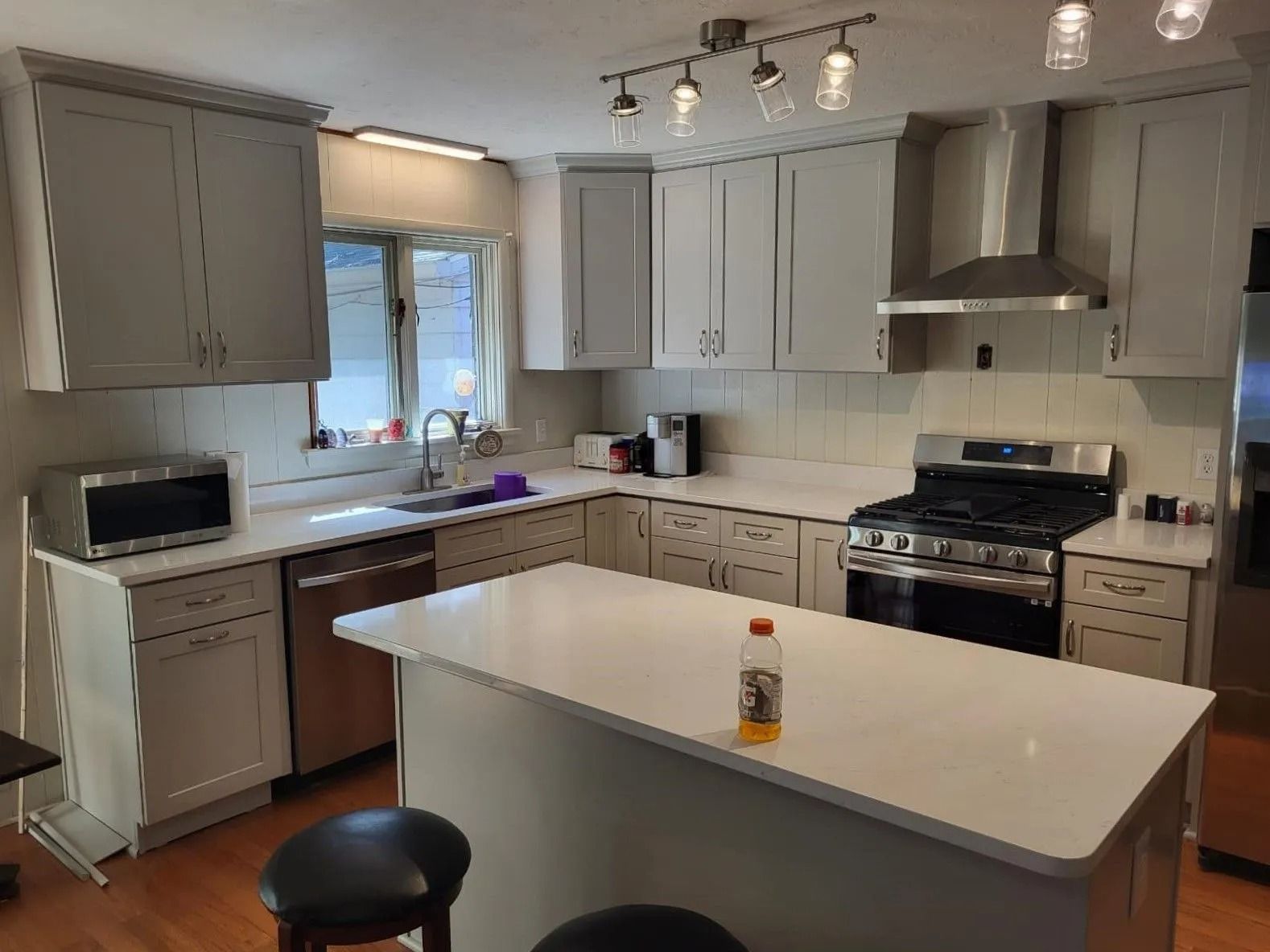 Modern kitchen with gray cabinets, white island, stainless range, and window over the sink