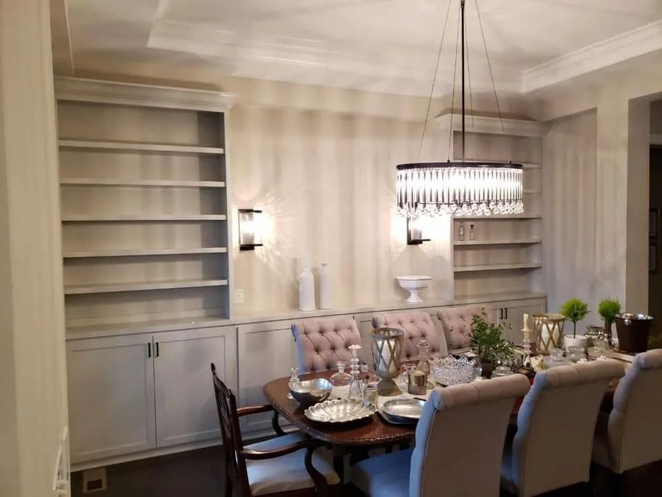 Elegant dining room with a tufted table, chandelier, striped walls, and built-in shelving