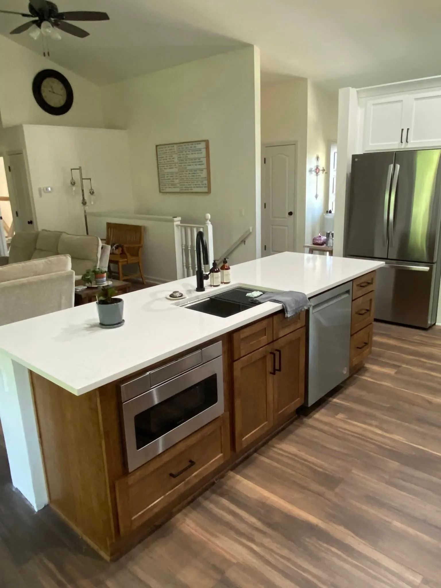 Modern kitchen with white island, wooden cabinets, stainless appliances, and a sink under bright lighting