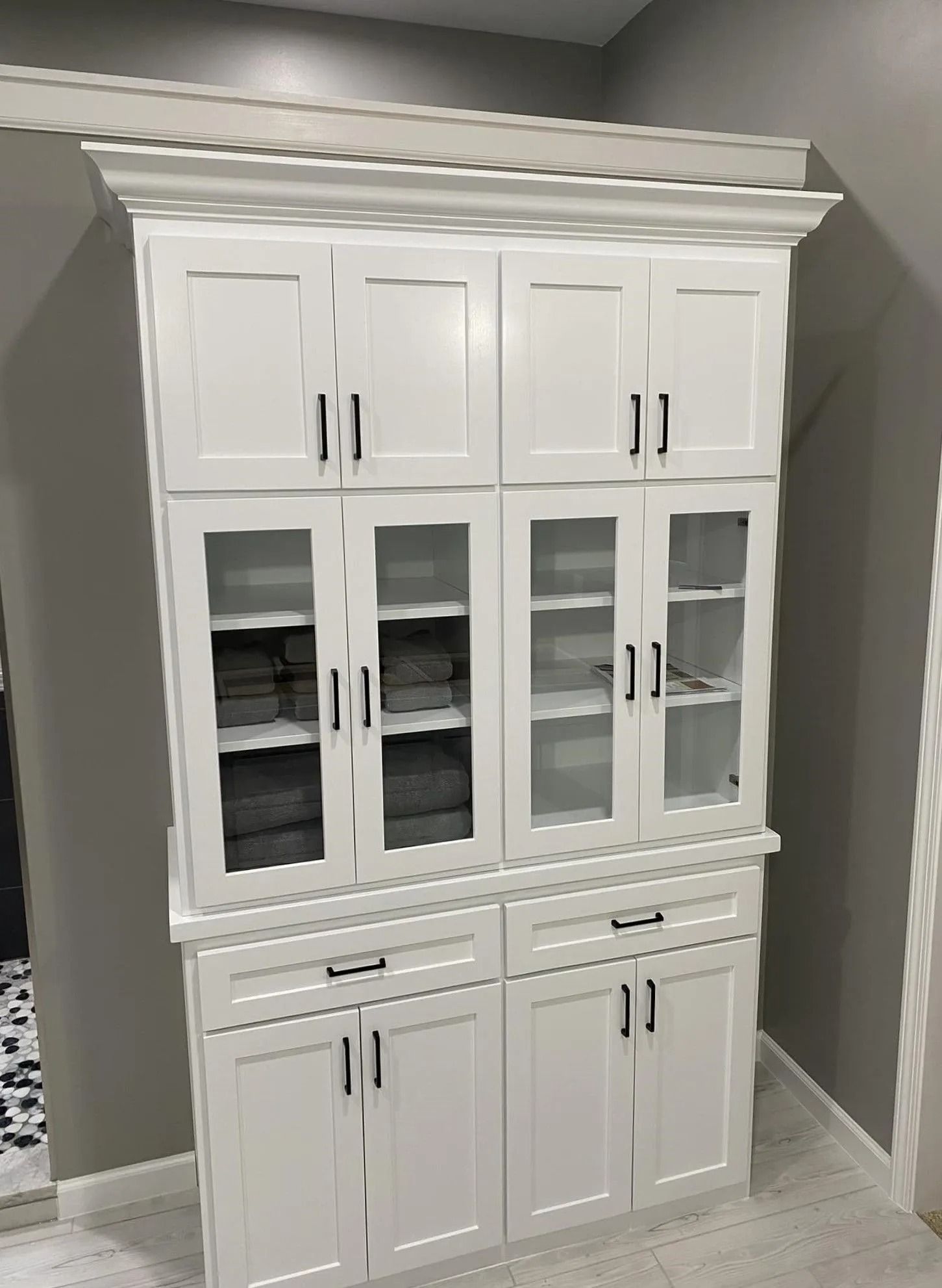 White cabinet with glass doors and drawers in a gray room