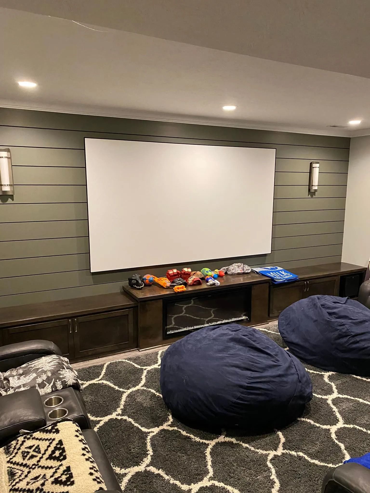 Home theater room with white screen, wall lights, snacks on a table, and two blue beanbag chairs