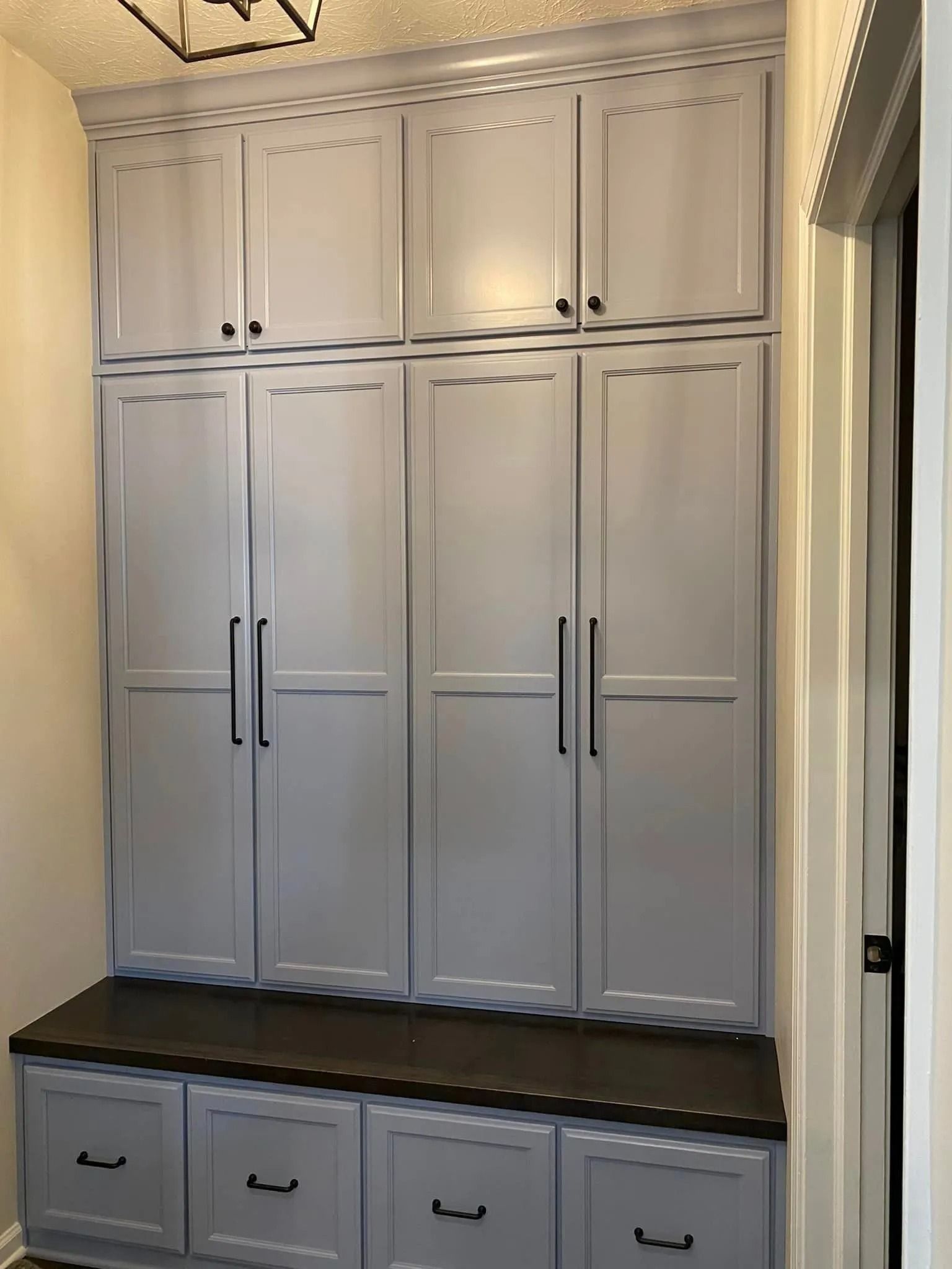 Built-in white cabinets with dark countertop and four drawers beneath in a hallway