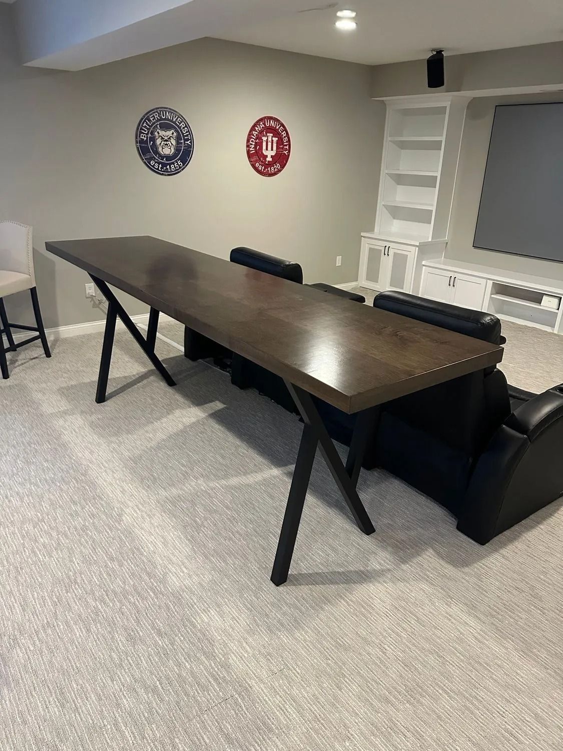 Modern conference room with a dark table, black chairs, wall emblems, and gray carpet