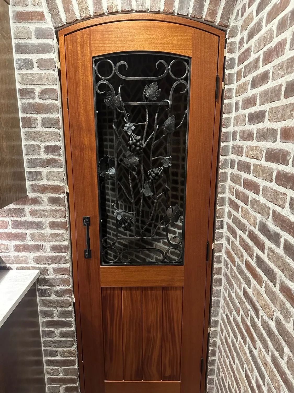 Wooden front door with decorative glass, set in a brick entryway.