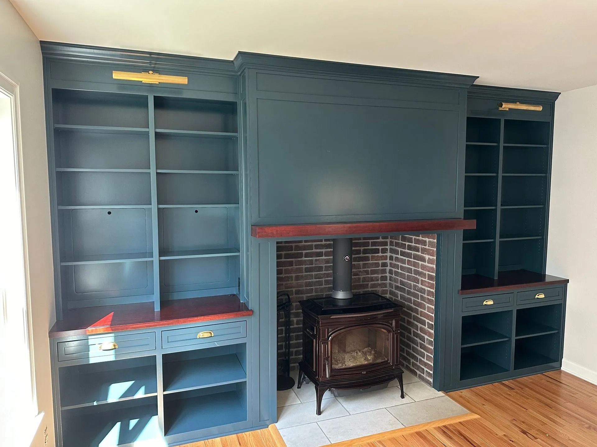 Blue built-in shelves flanking a brick fireplace with a wood stove in a living room