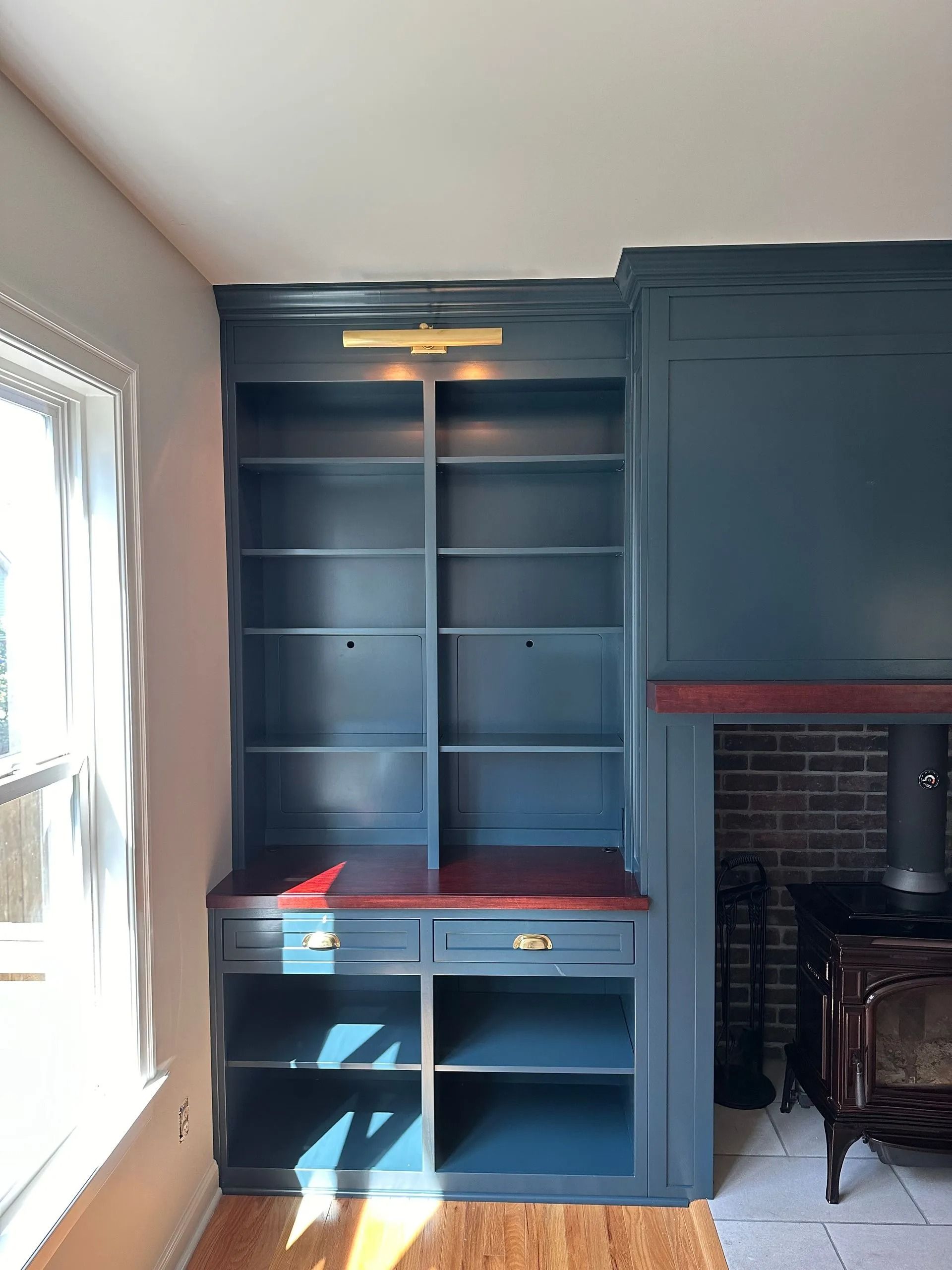 Blue built-in shelving and desk unit beside a fireplace in a sunlit room