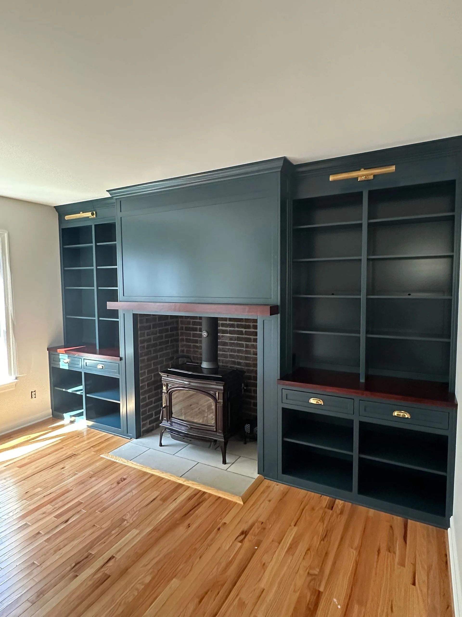 Built-in black bookshelves flanking a brick fireplace in a bright room with hardwood floors