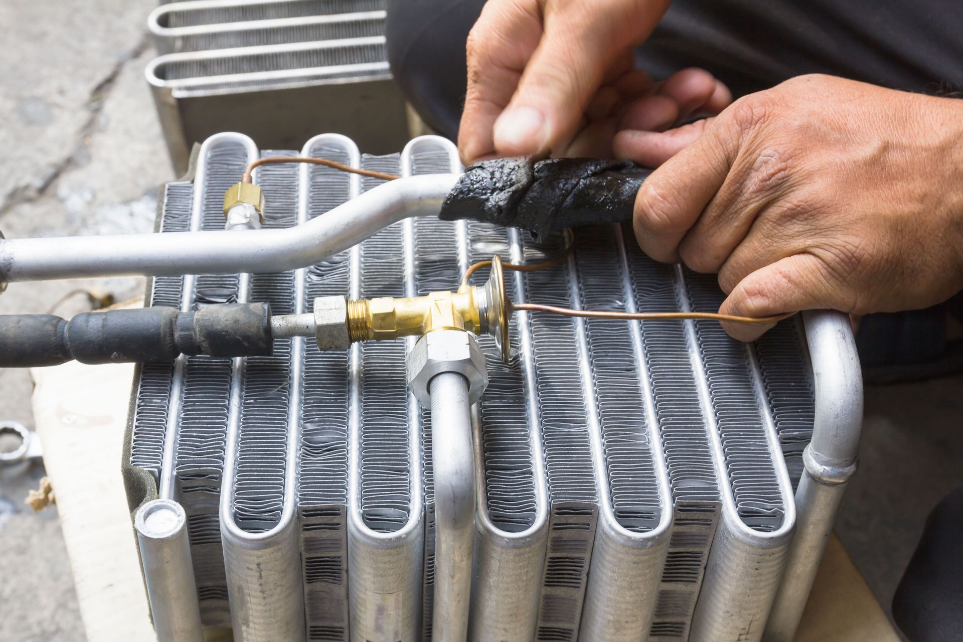 A man is working on a radiator with a hose attached to it.