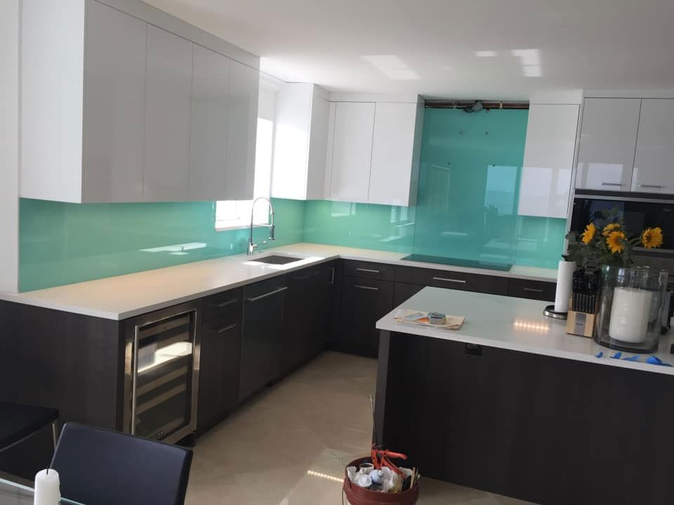 A kitchen with a green backsplash and white cabinets