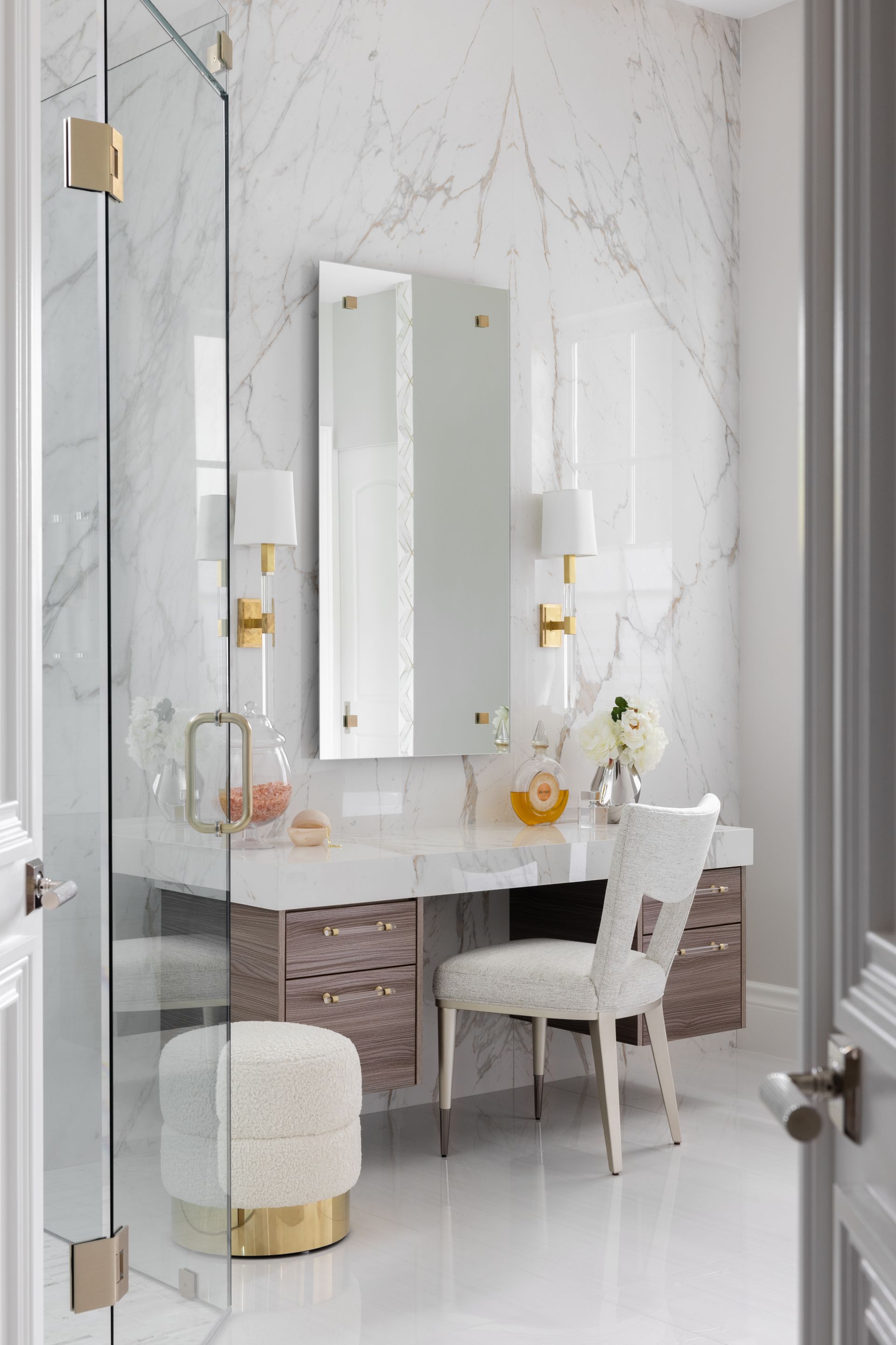A bathroom with a vanity, chair, mirror, and shower stall.