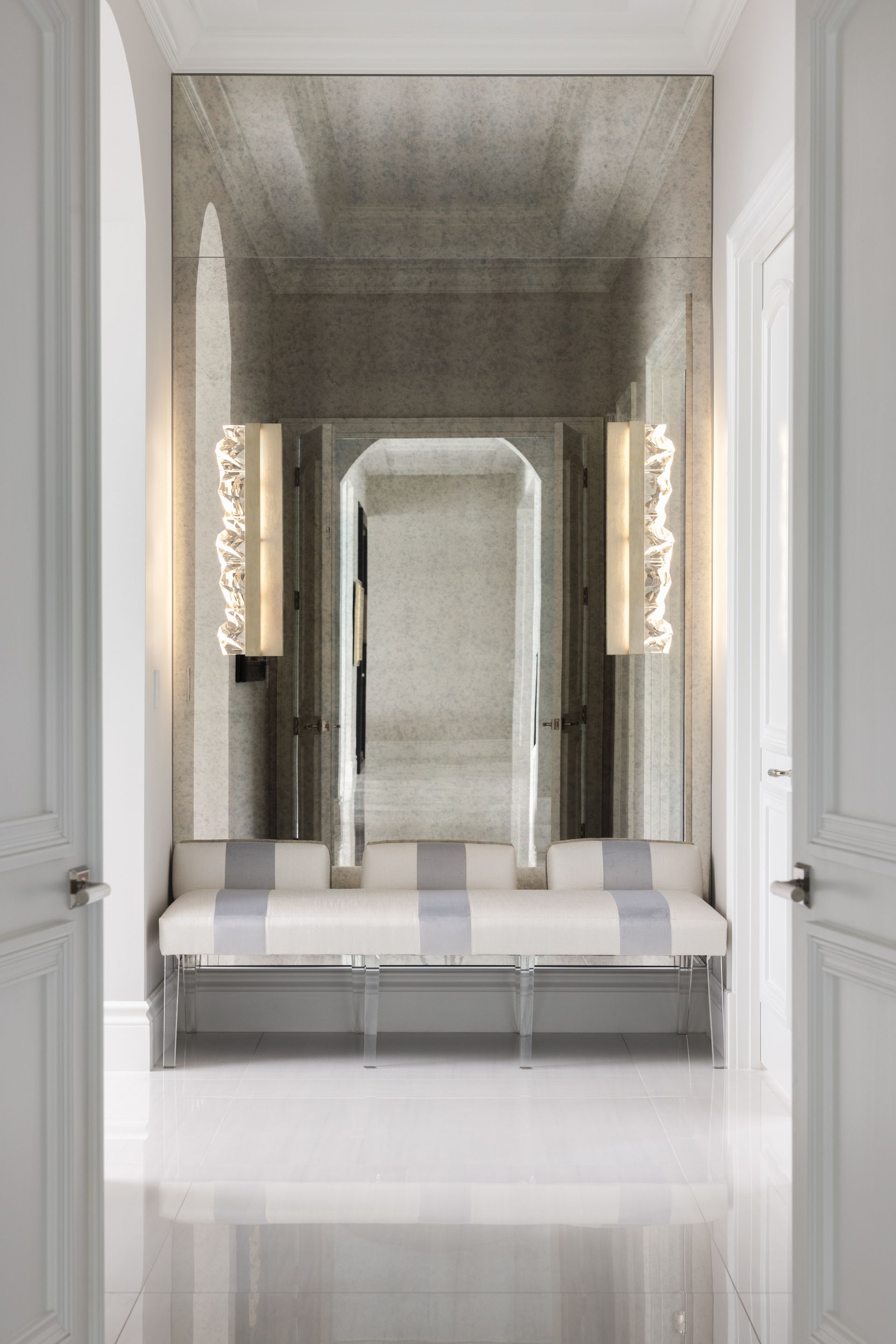 A hallway with a bench and a mirror on the wall.