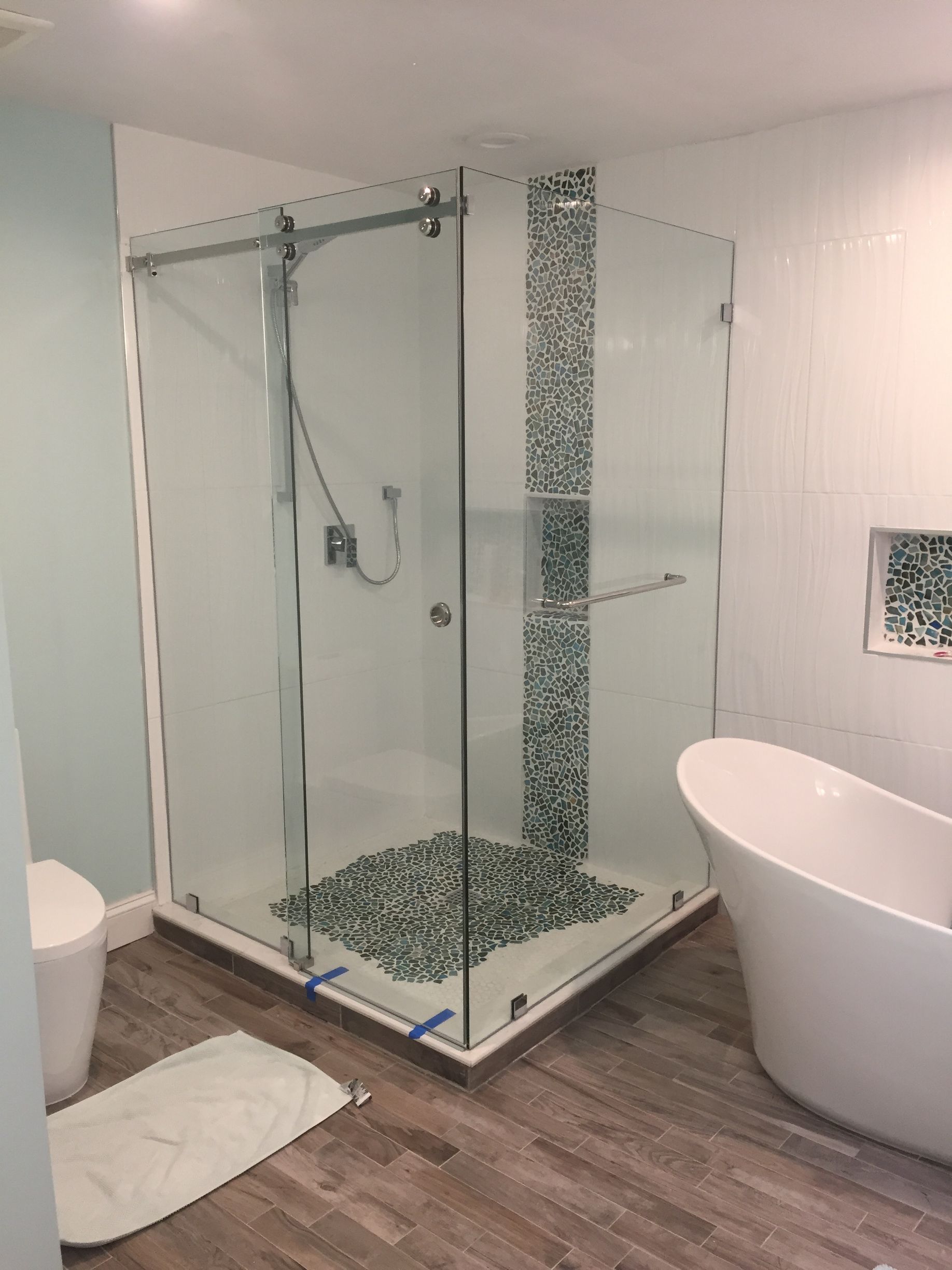 A bathroom with a tub, toilet, shower and shower stall.