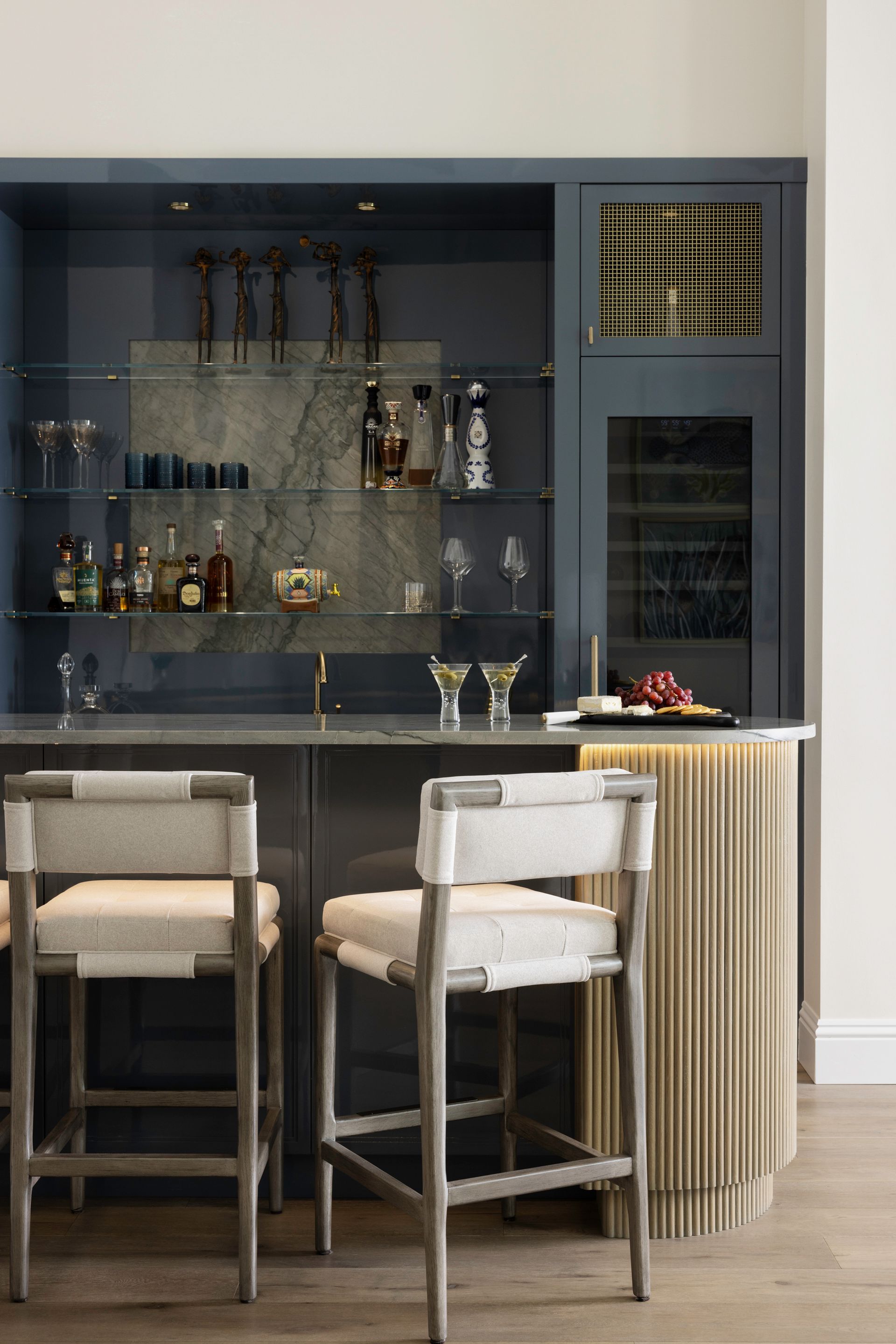 A bar with stools and a wine cooler in the living room.
