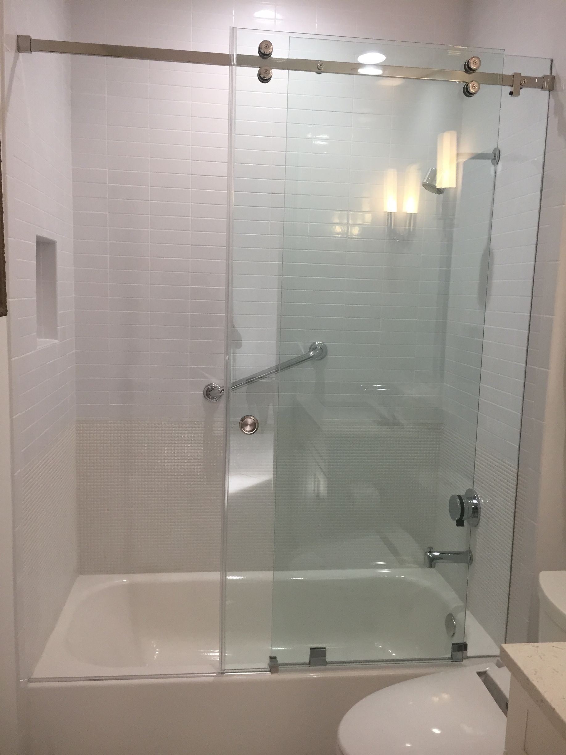 A bathroom with a sliding glass shower door over a bathtub.