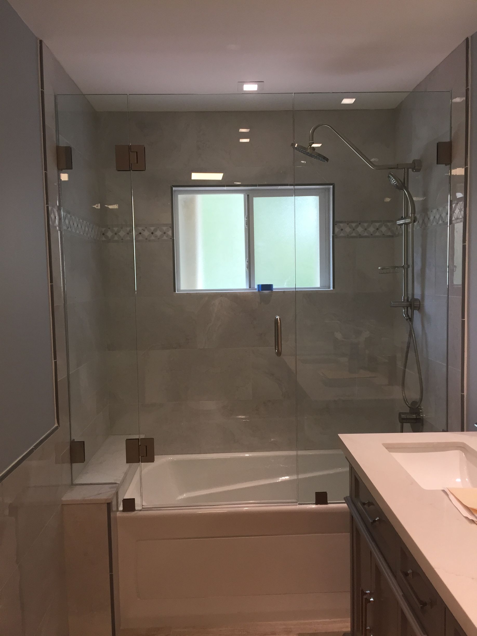 A bathroom with a tub, sink, shower and window.