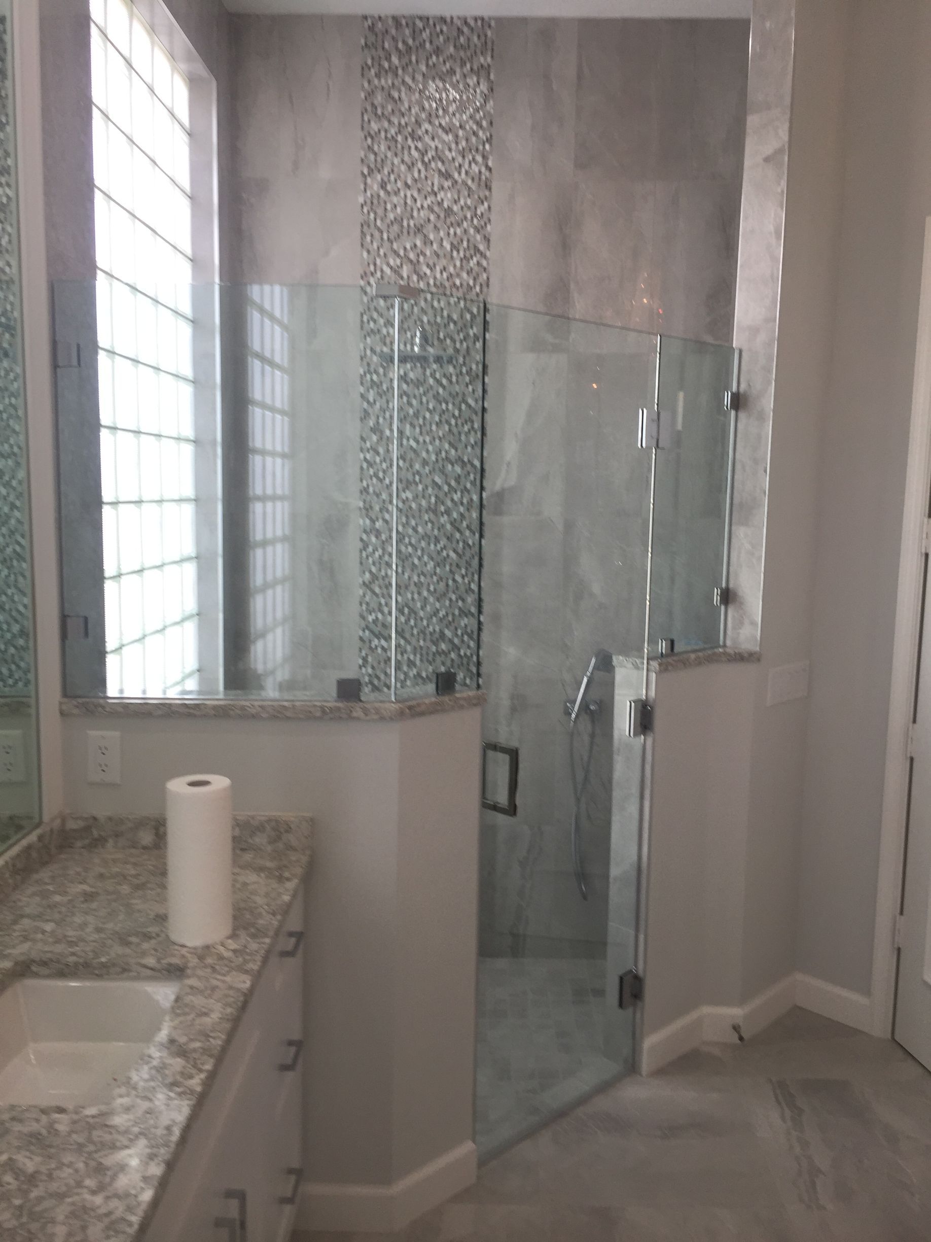 A bathroom with a glass shower door and a sink.