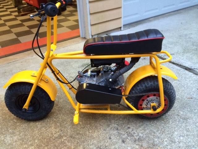 Yellow minibike with black engine, seat, and tires, set on a driveway.