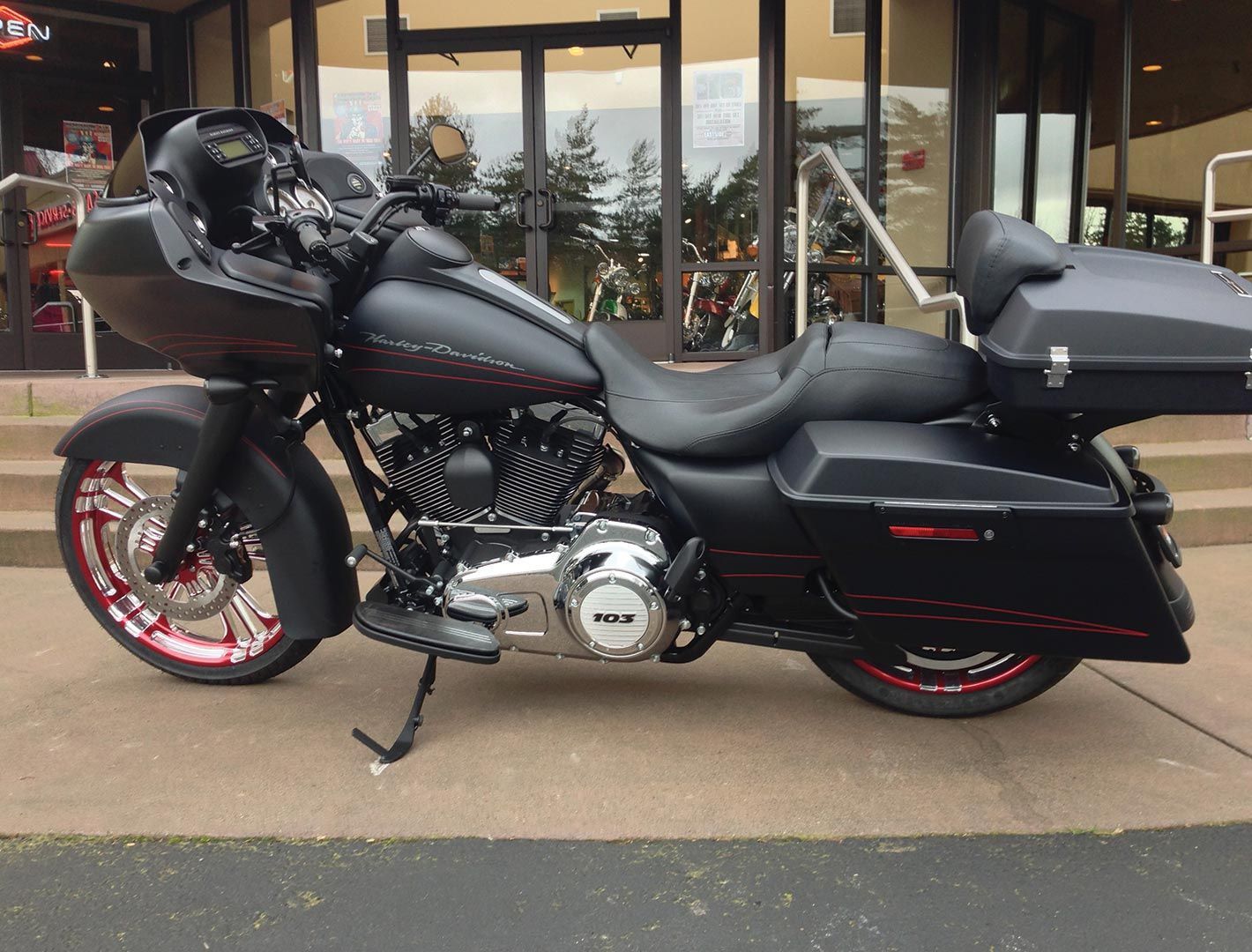 Black Harley-Davidson motorcycle with red accents parked outside a building with glass doors.