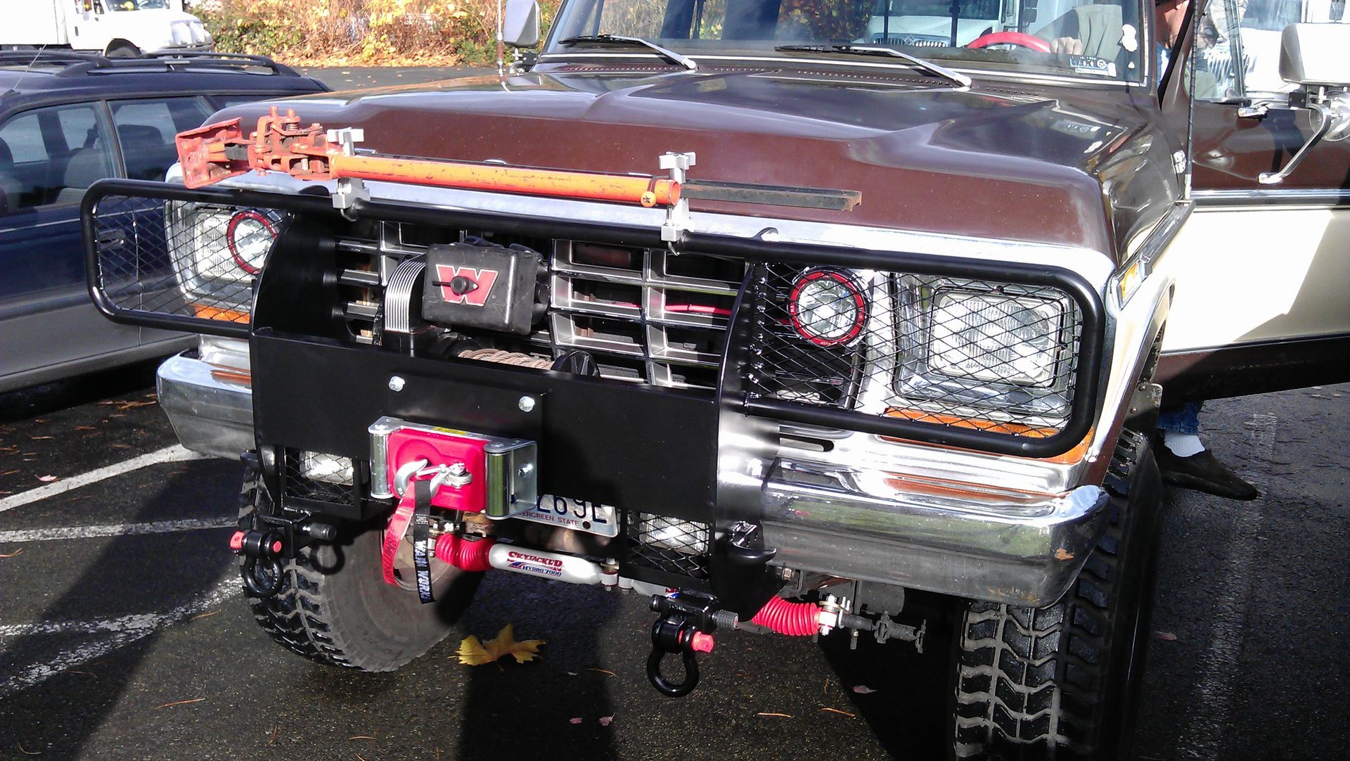 Brown vintage truck with custom front bumper, winch, and brush guard.