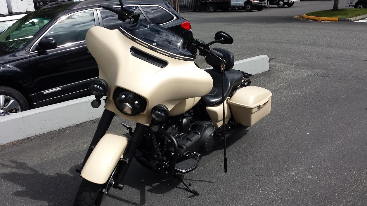 Tan motorcycle with fairing, saddlebags, and black accents parked on asphalt.