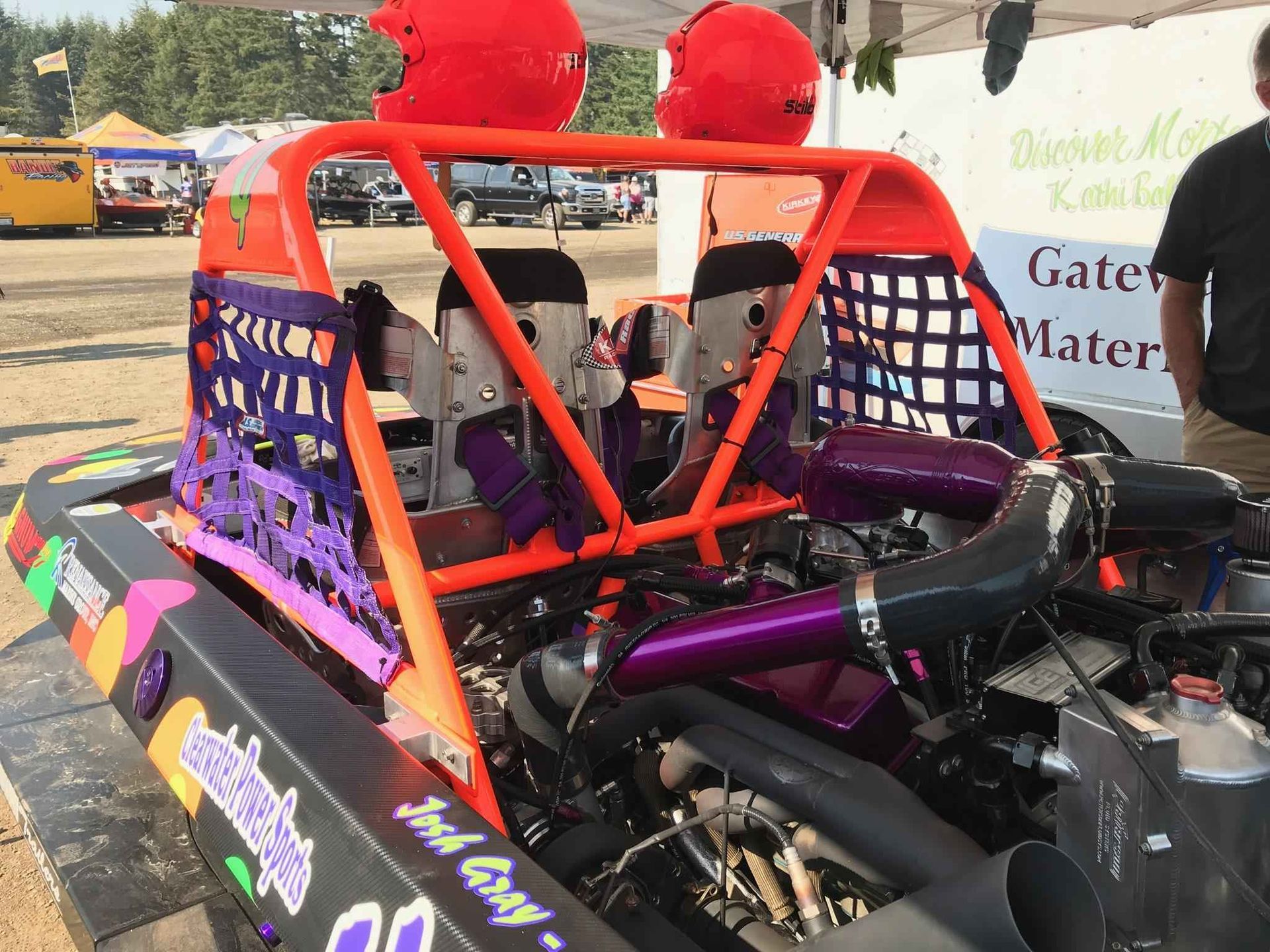 Race car with roll cage and two red helmets on top. Purple and orange details.