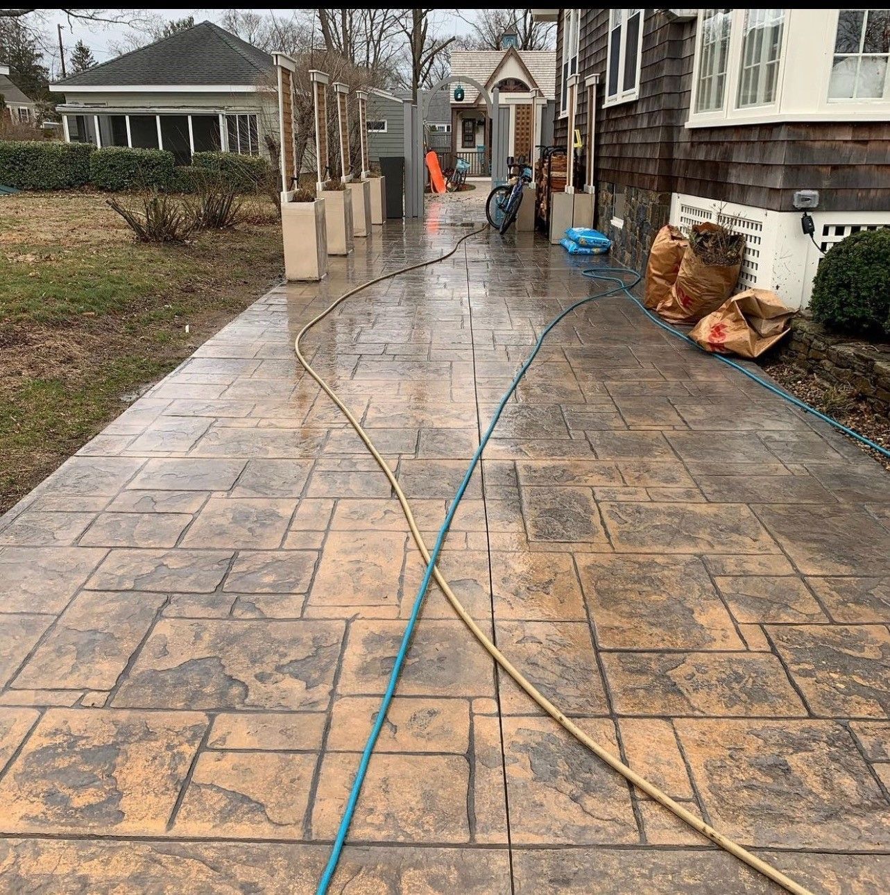 Person pressure washing a wet, patterned concrete walkway.