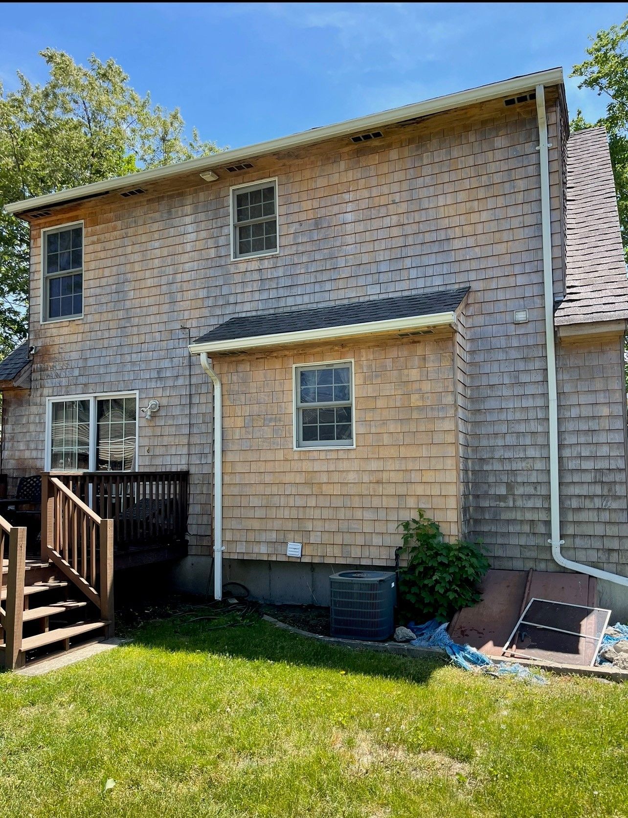 House exterior with cedar shake siding, windows, deck, and green lawn.
