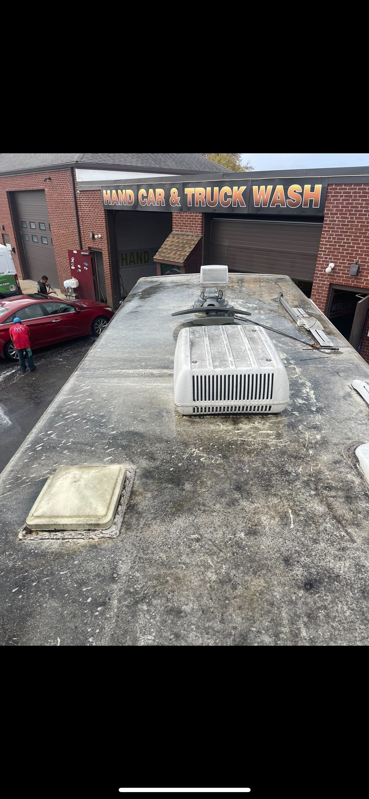 A view from atop a vehicle at a truck wash, showing the roof and the brick building with signage.