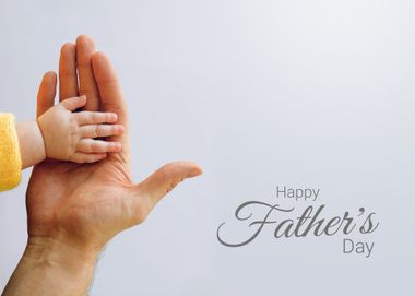 Adult and baby hands together with “Happy Father’s Day” text on a light background