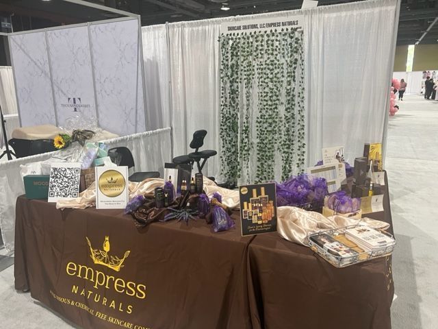 Empress Naturals booth with products on a brown table, backdrop, and logo.