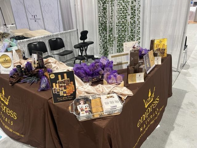 A booth at a trade show with Empress Naturals products, including bottles, boxes, and decor.