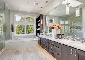 Modern bathroom with double vanity, large mirror, window seat, and white and dark wood finishes