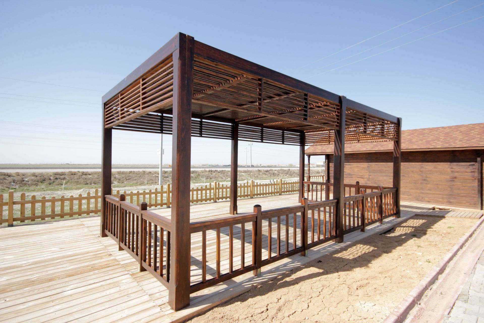Wooden shaded deck with railing overlooking a sandy desert landscape